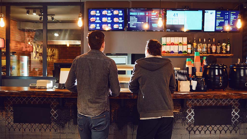Two men at a bar looking at ICRTouch TouchMenu digital menu screens