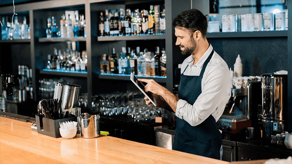 A server in a bar using an ICRTouch PocketTouch digital order taking tablet. Hospitality EPoS.