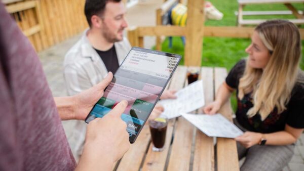 Couple ordering food at table via a waiter using ICRTouch PocketTouch digital ordering software on a tablet device