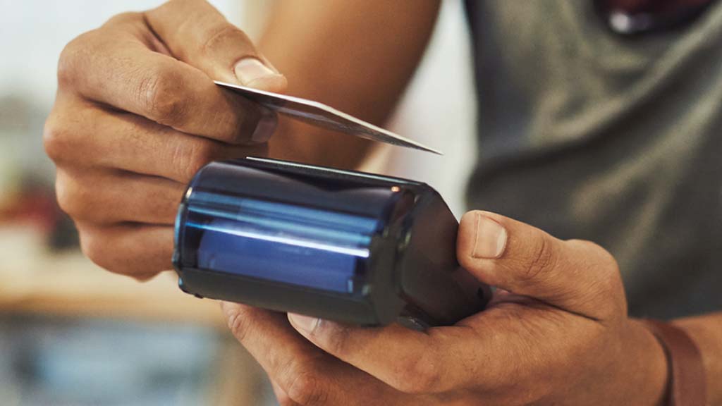 A customer using a handheld payment terminal to pay by contactless card