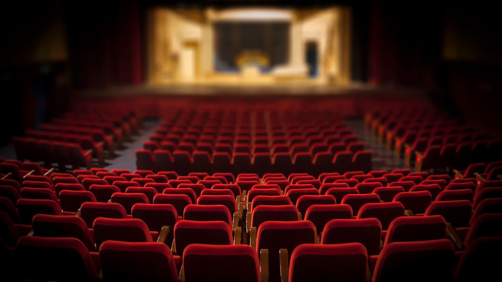 Theatre image showing rows of chairs with blurred stage in the background