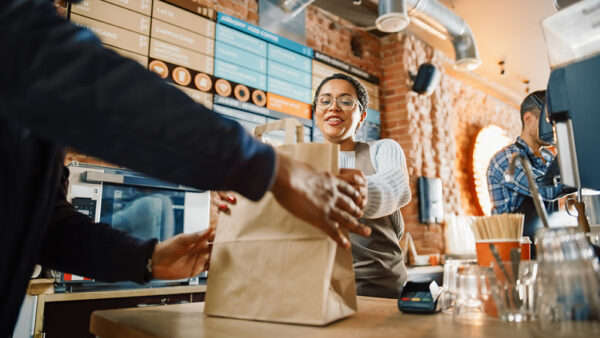 Masked staff member hands over takeaway food to customer wearing face mask